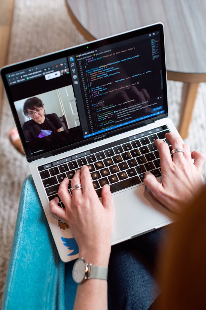 about-us Person coding on a laptop during a video conference, showcasing remote work.